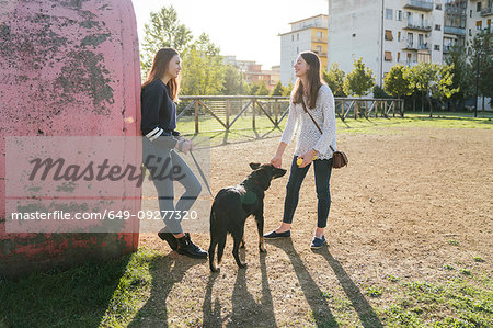 Sisters with dog talking in park