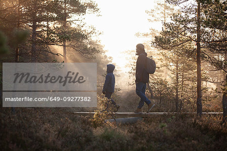 Father and son walking on planks in forest, Finland