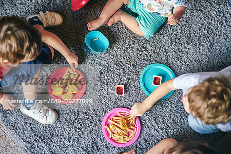 Children enjoying plates of food on rug