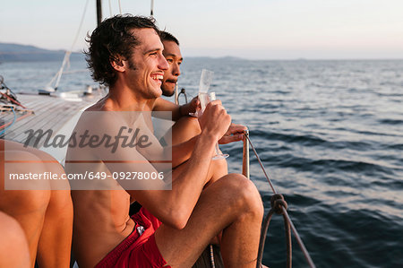 Young men enjoying champagne on sailboat, Italy