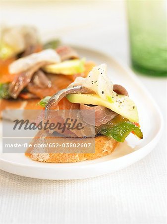 Smoked fish and grilled green peppers on a bite-size slice of bread