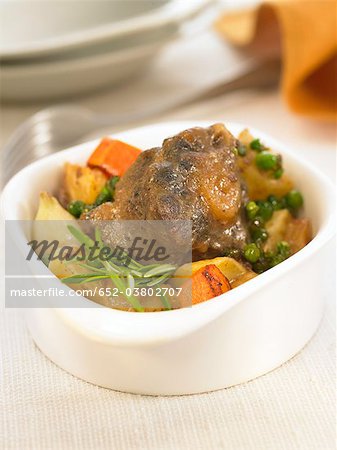 Small casserole dish of bull's tail with carrots and peas