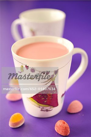 Cups of strawberry milk and candy gums Cups of strawberry milk and candy gums