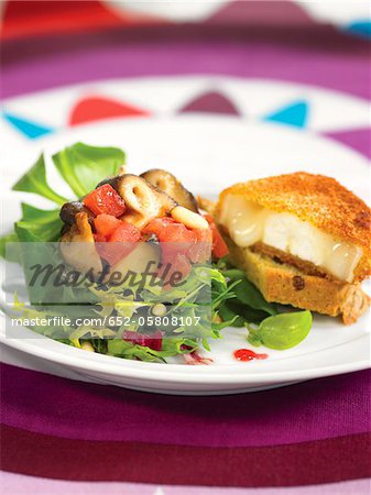 Fried goat's cheese coated in breadcrumbs with mixed salad and raspberry dressing