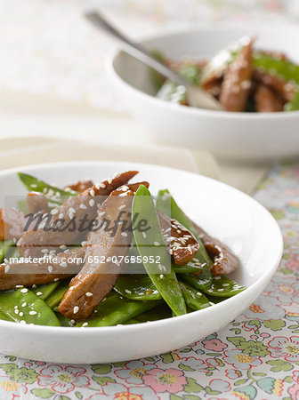 Thinly sliced duck breast with honey and sesame seeds,sugar peas