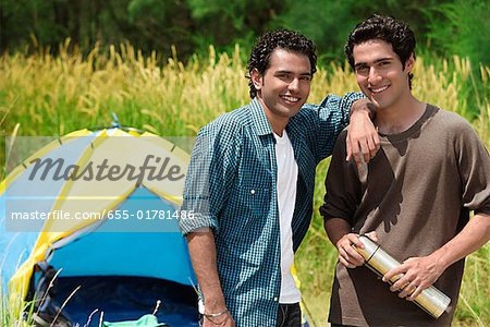 Two friends camping smiling at camera