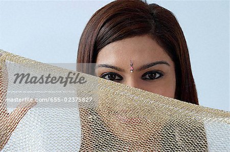 Young woman hiding behind veil