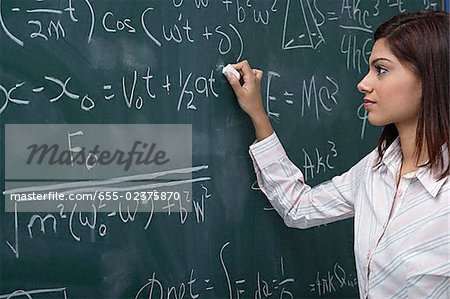 Woman working on equations on chalk board
