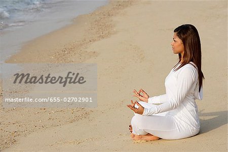 woman practicing yoga at the beach