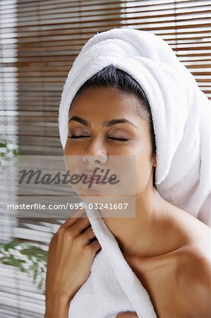 Indian woman closing her eyes relaxing with towel on her head