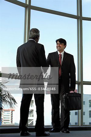 Indian business men shaking hands and smiling