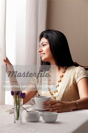 woman sitting at cafe and looking out the window