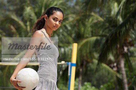 young woman holding volleyball at the beach