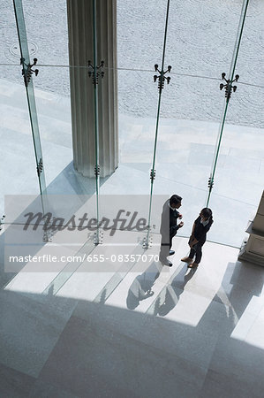 Looking down at two business people in discussion in lobby