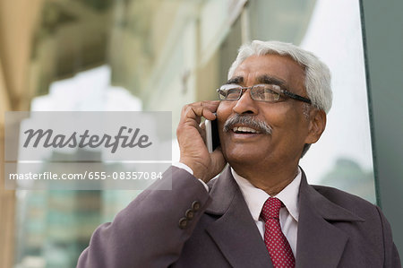 India, Smiling senior businessman talking on mobile phone