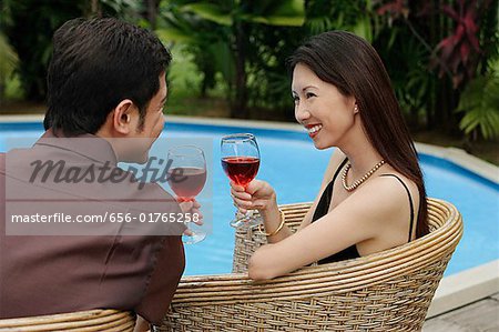 https://image1.masterfile.com/getImage/656-01765258em-couple-sitting-by-swimming-pool-holding-wine-glasses-stock-photo.jpg