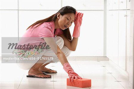 https://image1.masterfile.com/getImage/656-01765579em-woman-cleaning-kitchen-floor-with-big-pink-sponge-tired-stock-photo.jpg