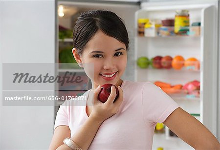Young woman holding apple and smiling at camera