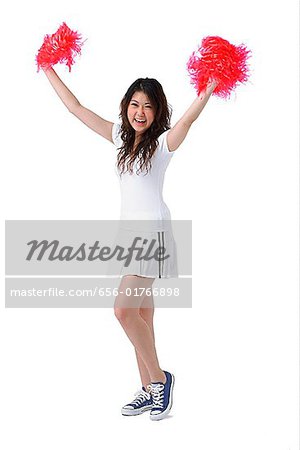 Young woman cheerleading with pom poms
