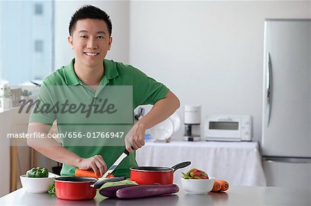 Man cutting vegetable and smiling at camera