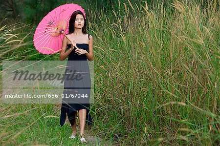 Woman walking in long grass with parasol