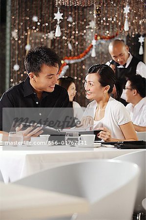 Couple in restaurant, holding menu, smiling at each other