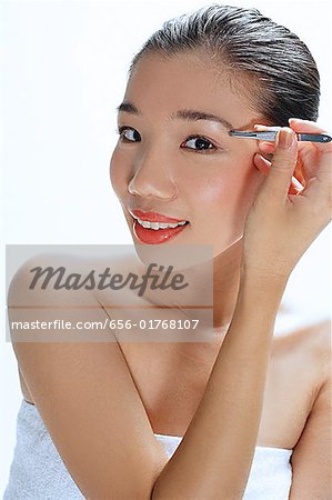 Woman applying eye shadow, looking at camera