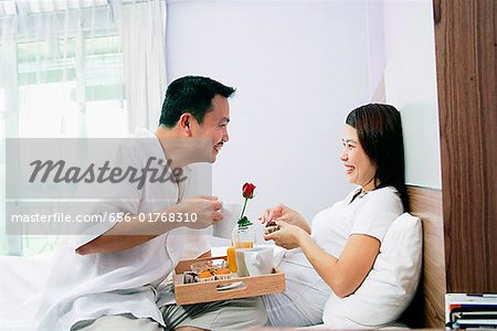 Couple in bedroom, breakfast tray between them