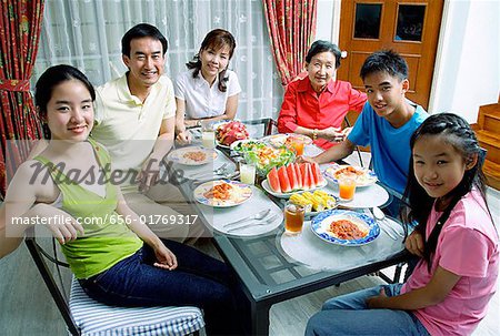 Three generation family around dining table, smiling at camera