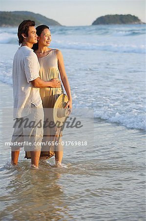 Couple standing on beach, ankle deep in water