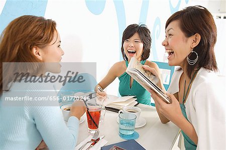 Young women in cafe, talking over drinks