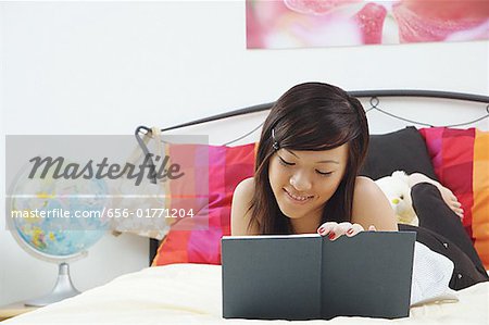 Girl lying on bed, writing in diary