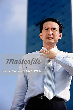 Businessman frowning, adjusting tie