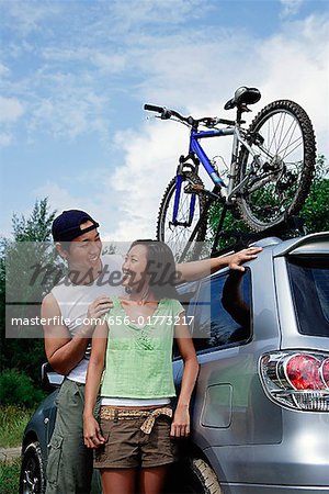 Couple standing next to SUV, looking at each other