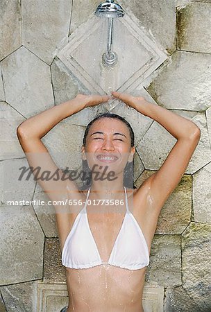 Young woman in white bikini, taking a shower