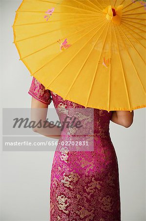 young Chinese woman in pink cheongsam holding yellow umbrella