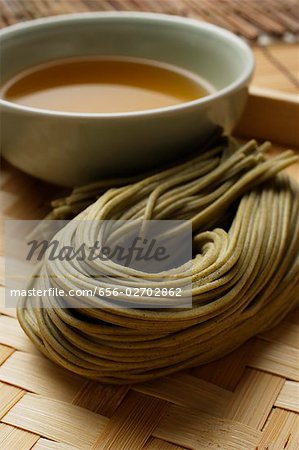 cooked soba noodles with sauce on the side placed on bamboo tray closeup