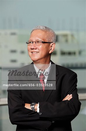 mature man wearing a suit smiling with arms crossed