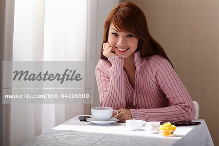 Young woman sitting at table near table with coffee.