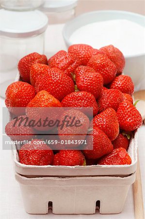 Fresh strawberries in cardboard punnet, jam jars, sugar