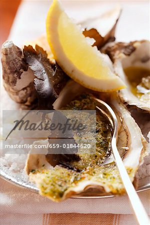 Baked oysters with herb breadcrumbs and lemon wedge