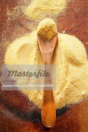 Polenta with wooden spoon on wooden background