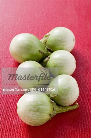 Green baby aubergines on red background