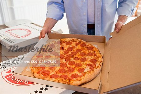 Man holding pizza box containing pepperoni pizza