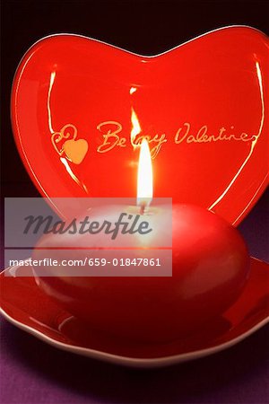 Red candle and heart-shaped plate for Valentine's Day