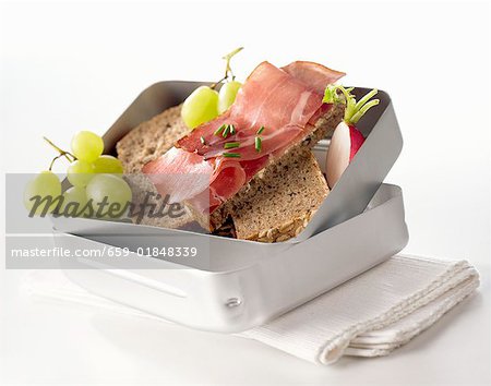 Ham sandwiches, radish and grapes in lunch box