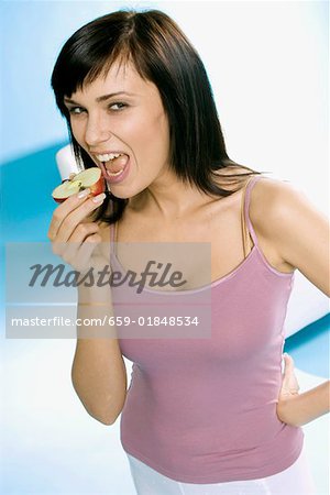 Young woman biting into half an apple