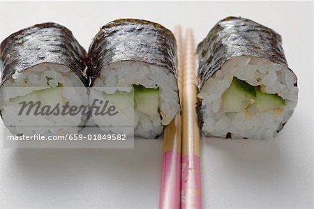 Three maki sushi with cucumber and chopsticks