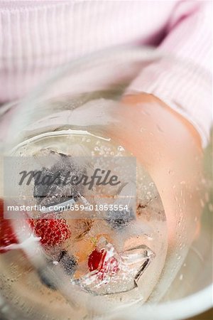 A glass of champagne with berry ice cubes