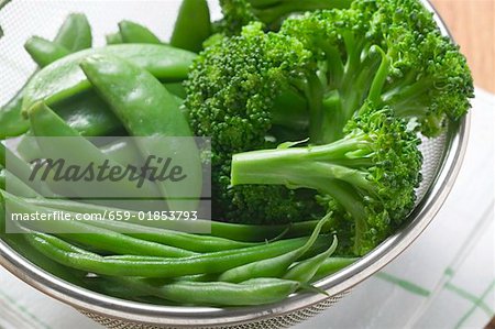 Cooked beans, mangetout and broccoli in a sieve